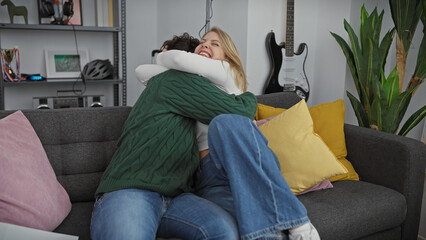 Obraz premium A joyful couple embraces on a couch in a cozy living room, depicting love and togetherness in a homely setting.