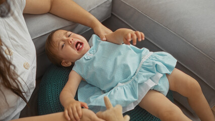 Woman comforting crying toddler daughter in living room showing family love and care