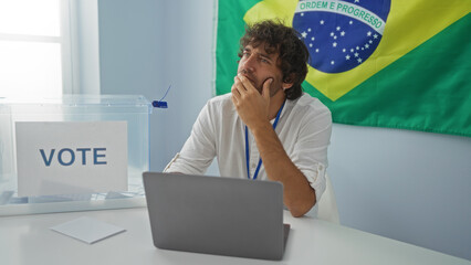 Young man in an electoral room in brazil with a voting box and flag in the background, looking...