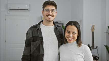 A smiling couple standing together in a modern living room with musical elements in the background.