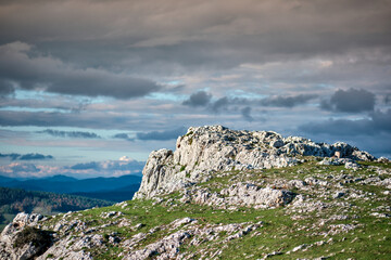 Rocky landscape with grassy foreground and dramatic cloudy sky