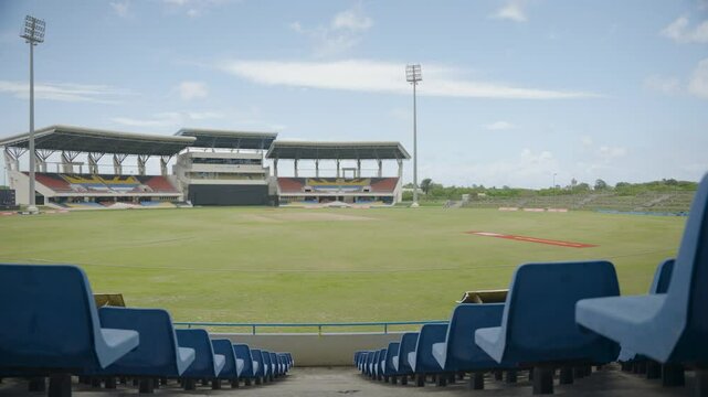 Centered shot of a cricket stadium, with seats on either side and the ground and stands in the middle in the distance. In Antigua in the Caribbean