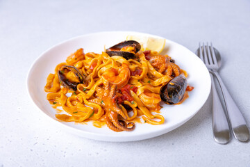 Marinara pasta with shrimps, octopus and mussels. Homemade noodles with seafood in tomato sauce. Traditional Italian dish. Selective focus, close-up.