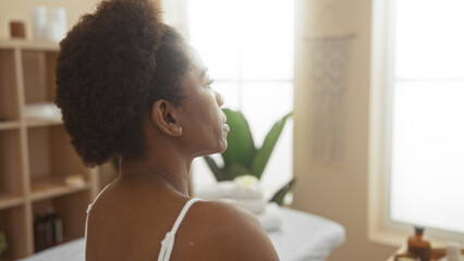 Beautiful black woman with curly hair relaxing in a wellness spa center, enjoying a peaceful moment...