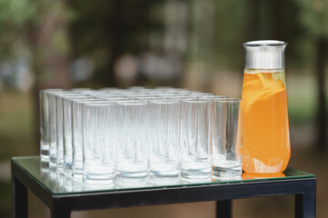 Refreshing beverage in a pitcher accompanies neatly arranged glasses outdoors