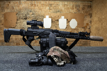 Tactical shooting at a shooting range, AK series rifle with a silencer, laser sight, flashlight and night vision device.