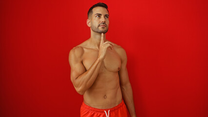 Young man thinking with his hand on chin over a red background isolated, showing deep thought and...
