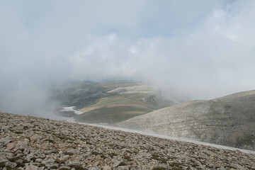 Snowy mountains and blue sky in the background. Snowy mountains with magnificent white clouds. Uludağ hiking routes. Clouds over Bursa Uludağ mountains. Blue sky, snowy and cloudy hills.