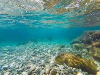 Underwater photo, transparent clear water on a beach with a rocky bottom in the south of France in Nice, Cote d'Azur.