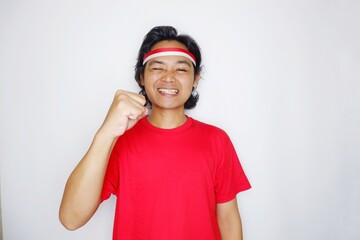 Portrait of an Indonesian man with long hair with a headband and red shirt celebrating Indonesian Independence Day with high nationalism on an isolated white background