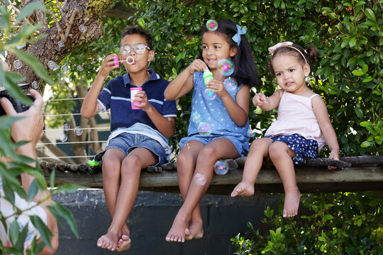 Children blowing bubbles on tree