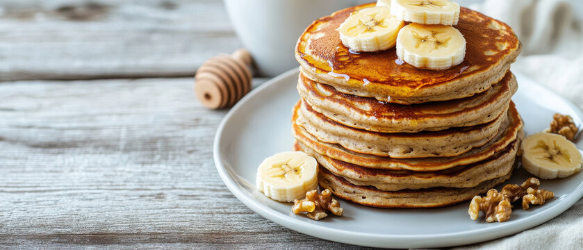 Stack of pancakes topped with banana slices and walnuts on a plate. - Powered by Adobe