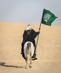 Arabian Warrior, riding his white stallion with Saudi Arabian flag in the empt quarter desert