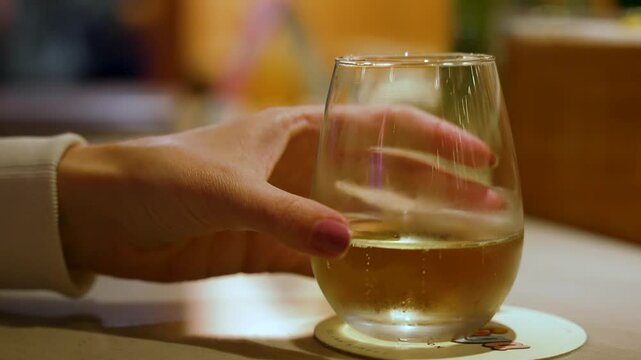 A female with manicured nails, grabbing a glass of wine and removing it from the counter