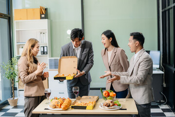Fototapeta premium Young Asian Professionals Celebrating with Pizza and Drinks in a Modern Office Setting