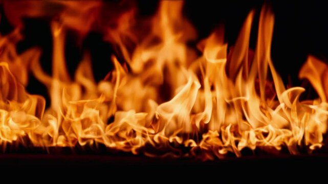 Beautiful dancing fire, the surface is ablaze. Lots of fire. Close-up immersion in the flames. The camera passes through the fire. Burning tongues of flame on a black backdrop in slow motion