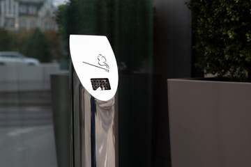 Metal ashtray on street for collecting waste from cigarette smokers, bad habit of smoking near building, conditions for smokers in special area