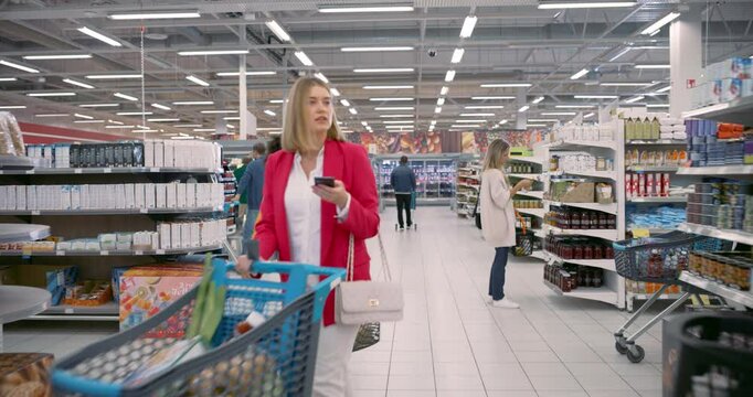 Group of Diverse Consumers, Including Children and Adults, Moves Through a Well-Stocked Supermarket. Families Pick Out Groceries and Dairy Products, while Some Check Offers on Packaged Foods