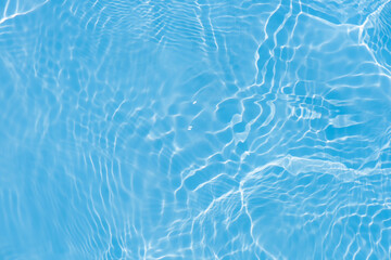 Blue water with ripples on the surface. Defocus blurred transparent blue colored clear calm water surface texture with splashes and bubbles. Water waves with shining pattern texture background.