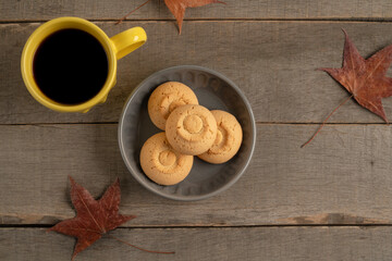 cup of coffee and cookies on wooden table with dried autumn leaves