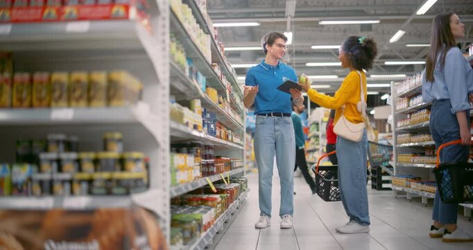 Supermarket Worker with a Tablet Computer Helping a Young African Shopper. Male and Female Having a Conversation, Manager Advising Customer on a Discounted Product. Girl is Happy with a Discount