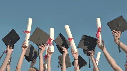 Happy graduates throwing graduation hats and diplomas in the air.