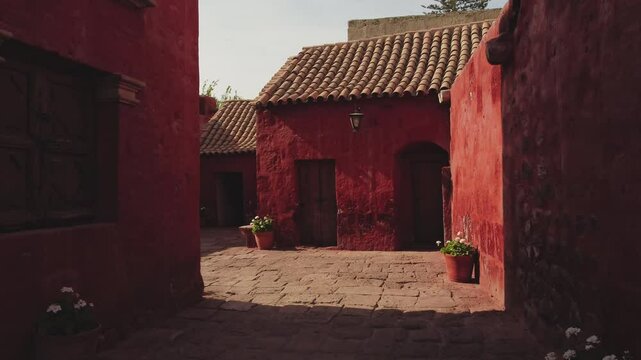 Walking along stone pavements, vibrant red walls contrast beautifully with the blue sky at santa catalina monastery