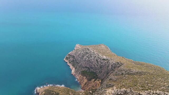 Aerial dolly of Punta de Toix in Calpe, Spain, showcasing the rugged coastline and turquoise waters under a clear blue sky