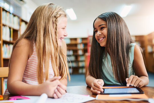 Tablet, child and friends in library for learning, education or reading info for knowledge. Happy students, girl and smile on tech at school for studying, teamwork or watch online course together
