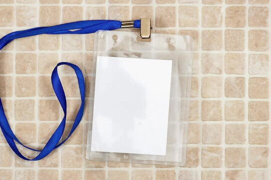 Blank badge mockup. Plain empty name tag mock up on mosaic tiles. Name tag with blue ribbon and transparent plastic paper holder. Badge clipping path. Corporate design
