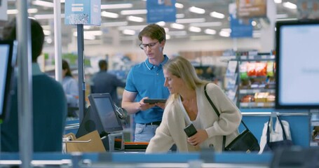 Store Manager Helping Female Shopper to Use a Self-Service Checkout in a Modern Supermarket, Scanning Her Groceries One by One. Woman Pays Using Her Smartphone for a Contactless Payment
