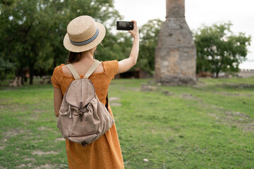 Woman taking photo at historical site with smartphone outdoors