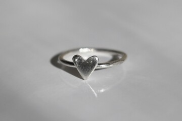 Elegant silver ring with small heart on white background for everyday wear and gifts.