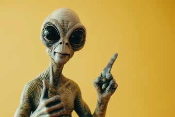 funny portrait of a grey alien pointing up on yellow copy space background
