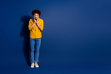 Full body portrait of nice young man look down empty space wear yellow shirt isolated on dark blue color background