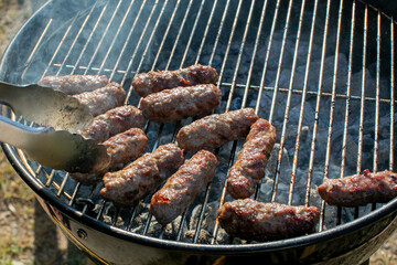 Grilling delicious traditional Balkan cevapi sausages on a smoky barbecue grill, perfect for summer gatherings and outdoor festive celebrations