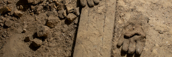 Dirty work gloves abandoned on rocky terrain, symbolizing Labor Day and construction industry...