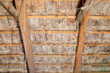 Close-up of a deteriorating wooden attic ceiling with exposed beams, related to home renovation and structural integrity issues
