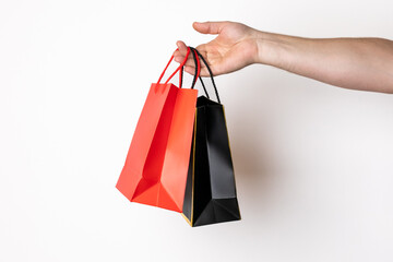 Close-up of a Caucasian person's hand holding colorful shopping bags, representing retail therapy...