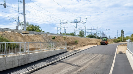 Naklejka premium Road construction near railway tracks highlighting infrastructure development and transportation improvements on a sunny day