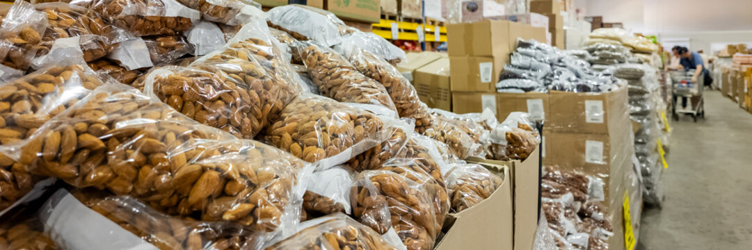 Bags of almonds stacked in bulk at a wholesale warehouse, illustrating food stocking and supply chain management for businesses