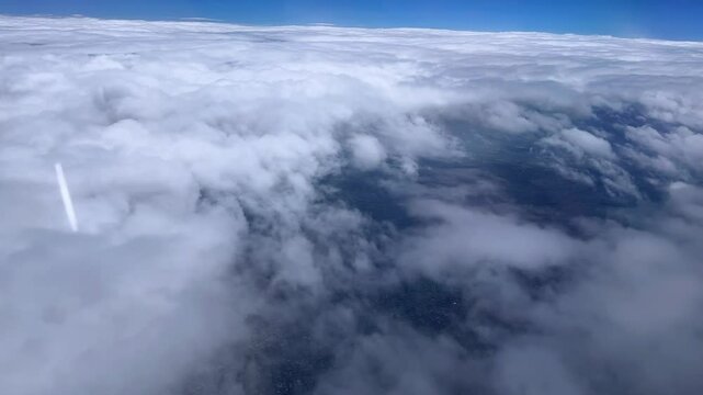 Thick clouds with a distant jet stream cutting through the sky, aerial view