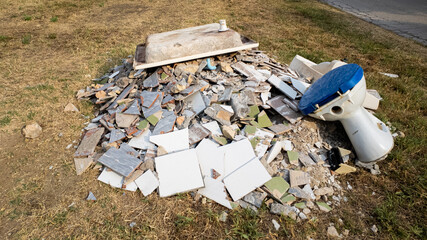 A pile of construction debris and an old toilet discarded improperly, highlighting the issue of...
