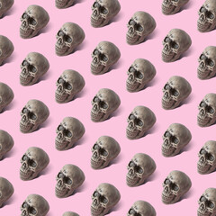 Halloween skull pattern on pink background. Minimal holiday concept.