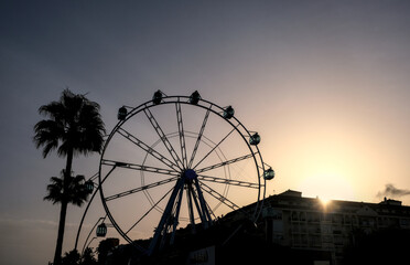 Estepona Ferris wheel sunset with buildings in the background and palm trees, Malaga, Spain