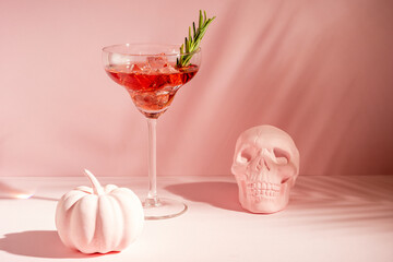 Halloween minimal concept with pink pumpkin, skull and cocktail. Creative holiday party background.