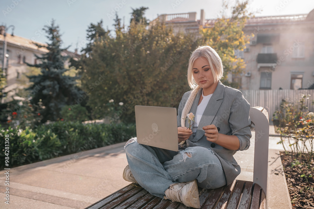 Wall mural a woman is sitting on a bench with a laptop in front of her