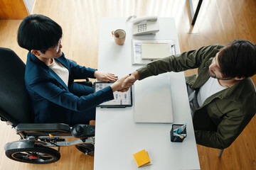 High angle view of businesswoman shaking hand to her partner at meeting