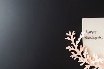 A Thanksgiving greeting card featuring a handwritten 'Happy Thanksgiving' message with decorative white leaves on a dark background, exuding festive warmth.