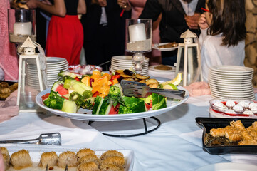 Close-up of a vibrant fruit plate on a party table, featuring an assortment of fresh fruits. Plate is surrounded by various sweets, desserts, and festive decorations, creating celebratory atmosphere